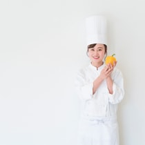 Young chef holding a piment and smiling