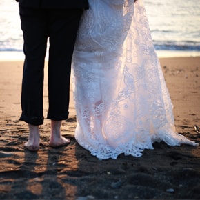 Newly wed's legs on a beach as the sun is setting.